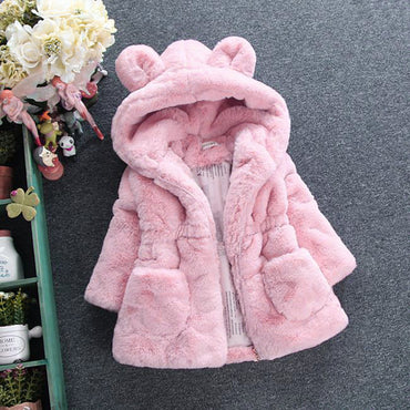 Pink children's coat with bear ears on a gray surface